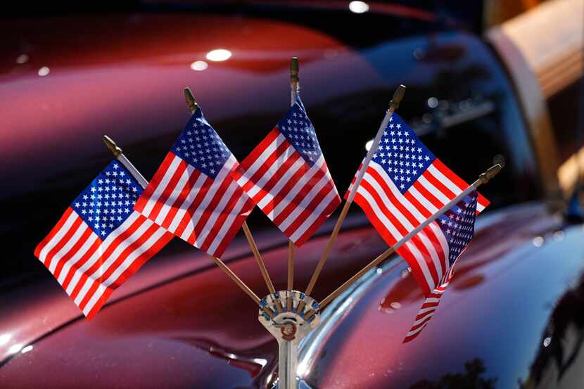 American flags splay out in a display attached to the fender crest of a 1948 Pontiac Silver...