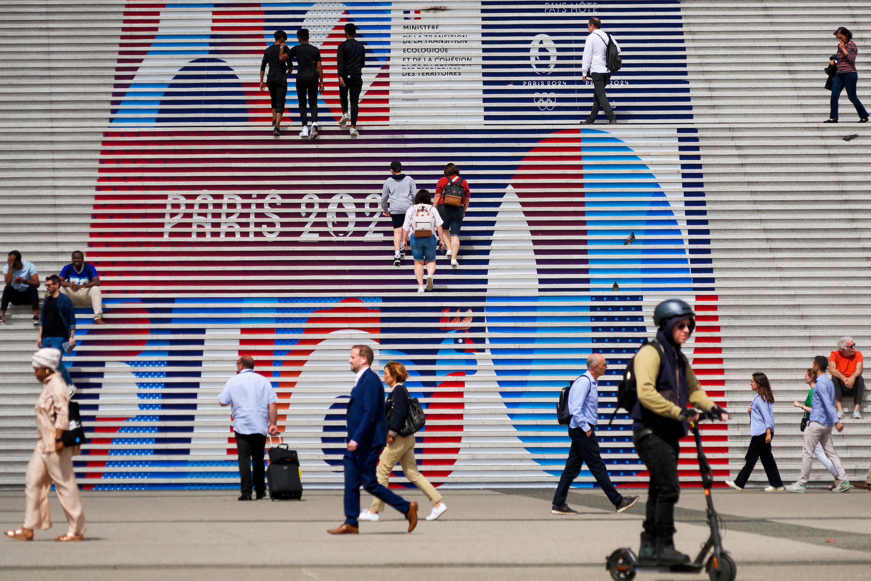 People gather on a stairway to La Grande Arche de la Défense, near the swimming venue, ...