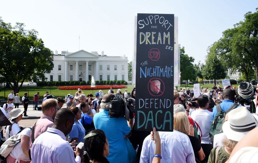 Protesters hold up signs during a rally supporting Deferred Action for Childhood Arrivals,...