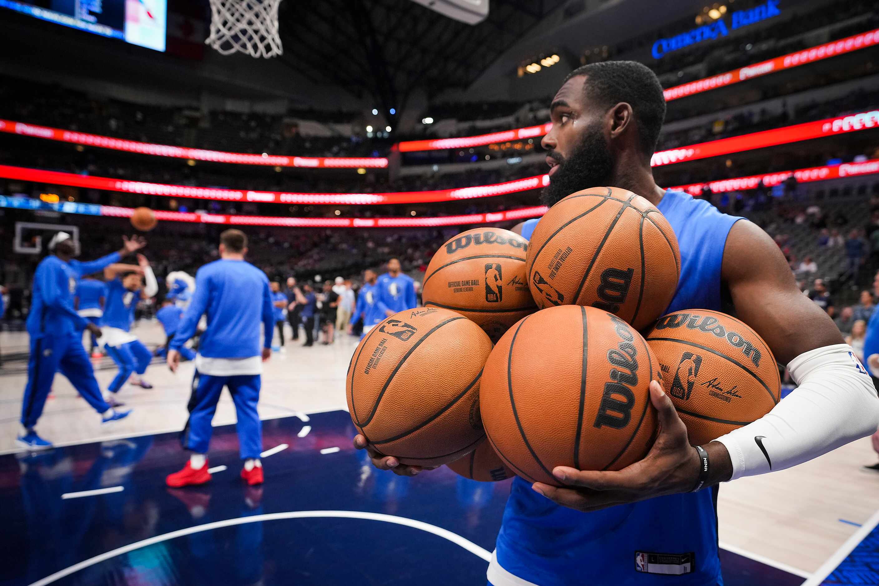 Dallas Mavericks forward Tim Hardaway Jr. grabs up basketballs as he warms up before an NBA...