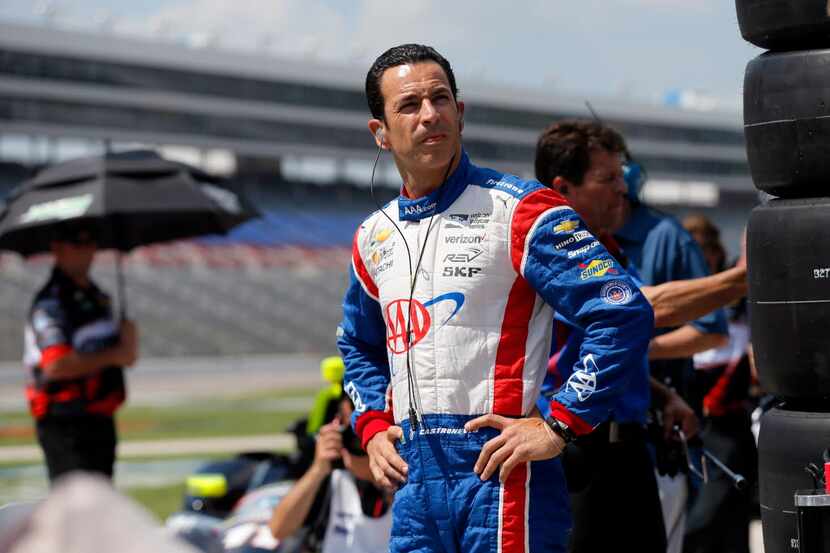 Helio Castroneves of Brazil stands on pit road by his car during qualifying for an IndyCar...