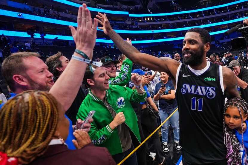 Dallas Mavericks guard Kyrie Irving celebrates with fans as he leaves the court with his...