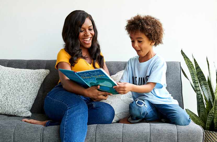 woman and child sitting on a couch reading a book