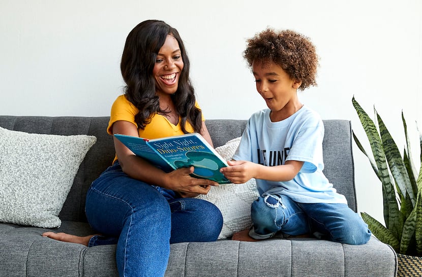 woman and child sitting on a couch reading a book