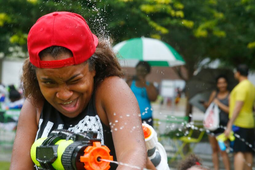 People squirt water on each other during a watergun flash mob at Klyde Warren Park in Dallas...