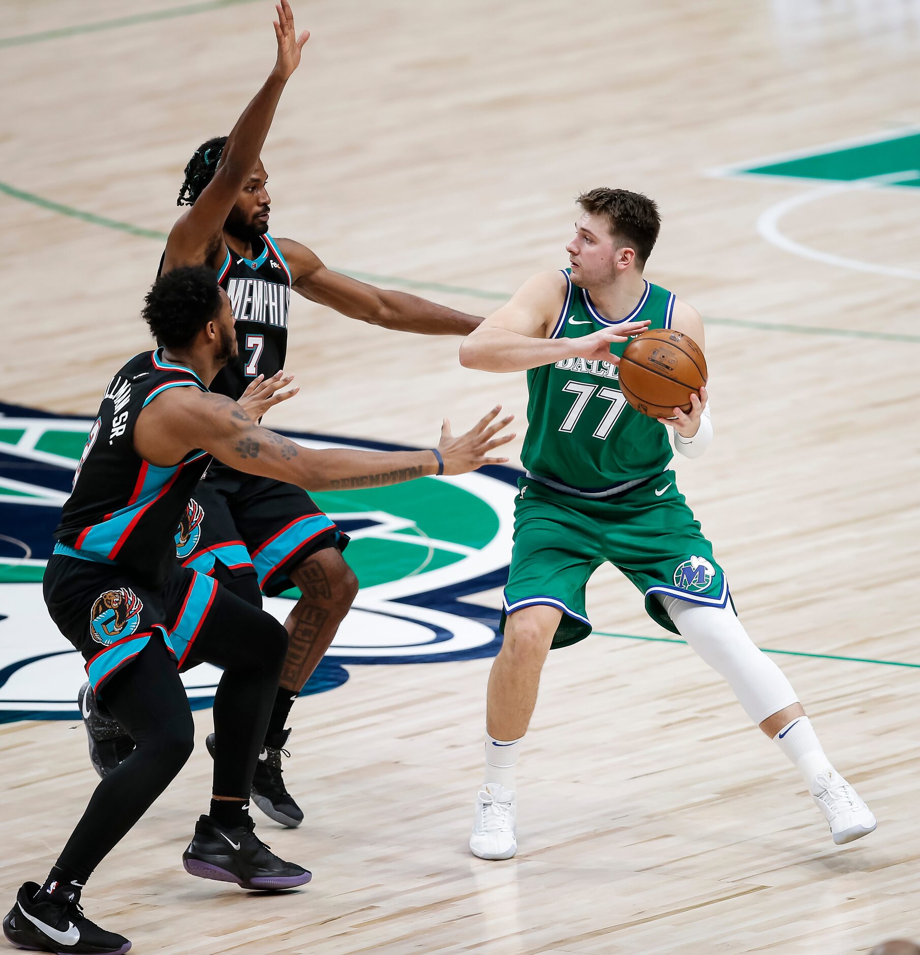 Dallas Mavericks guard Luka Doncic (77) looks for room against Memphis Grizzlies forwards...