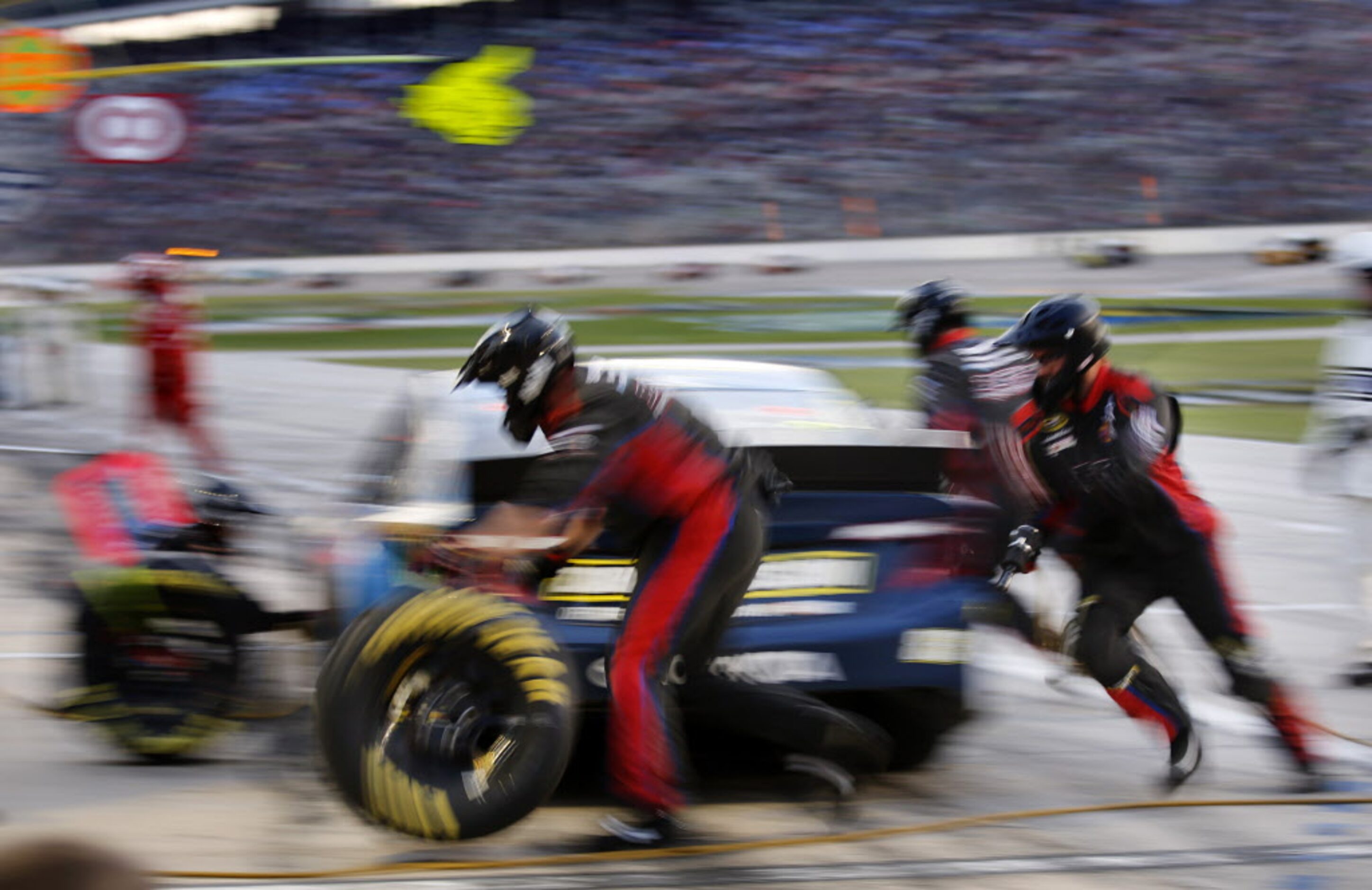 Crewman for Sprint Cup Series driver Ryan Truex (83) race around the car making a four-tire...