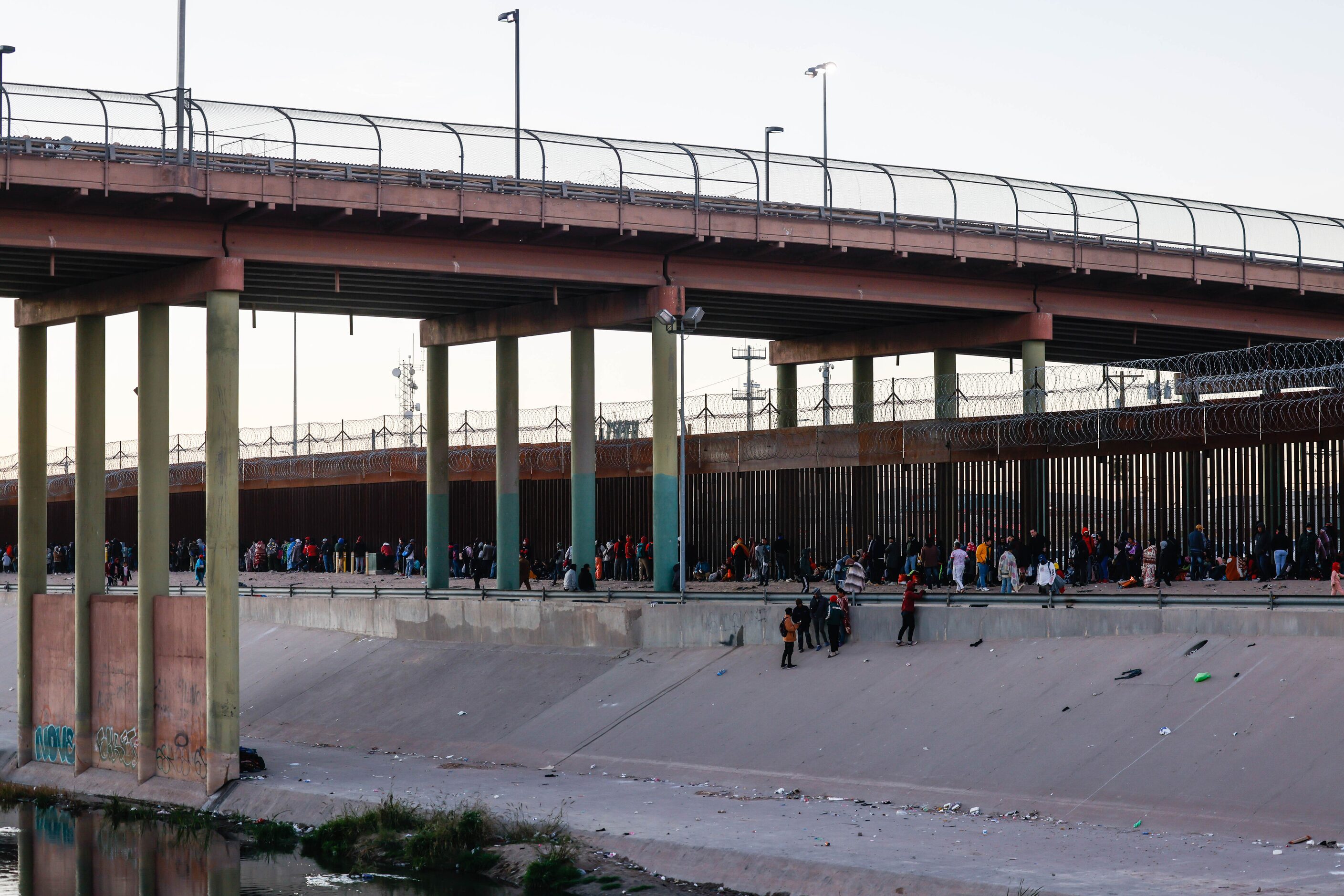 Migrants stand in line at a US-Mexico border gate from the banks of the Rio Grande River in...