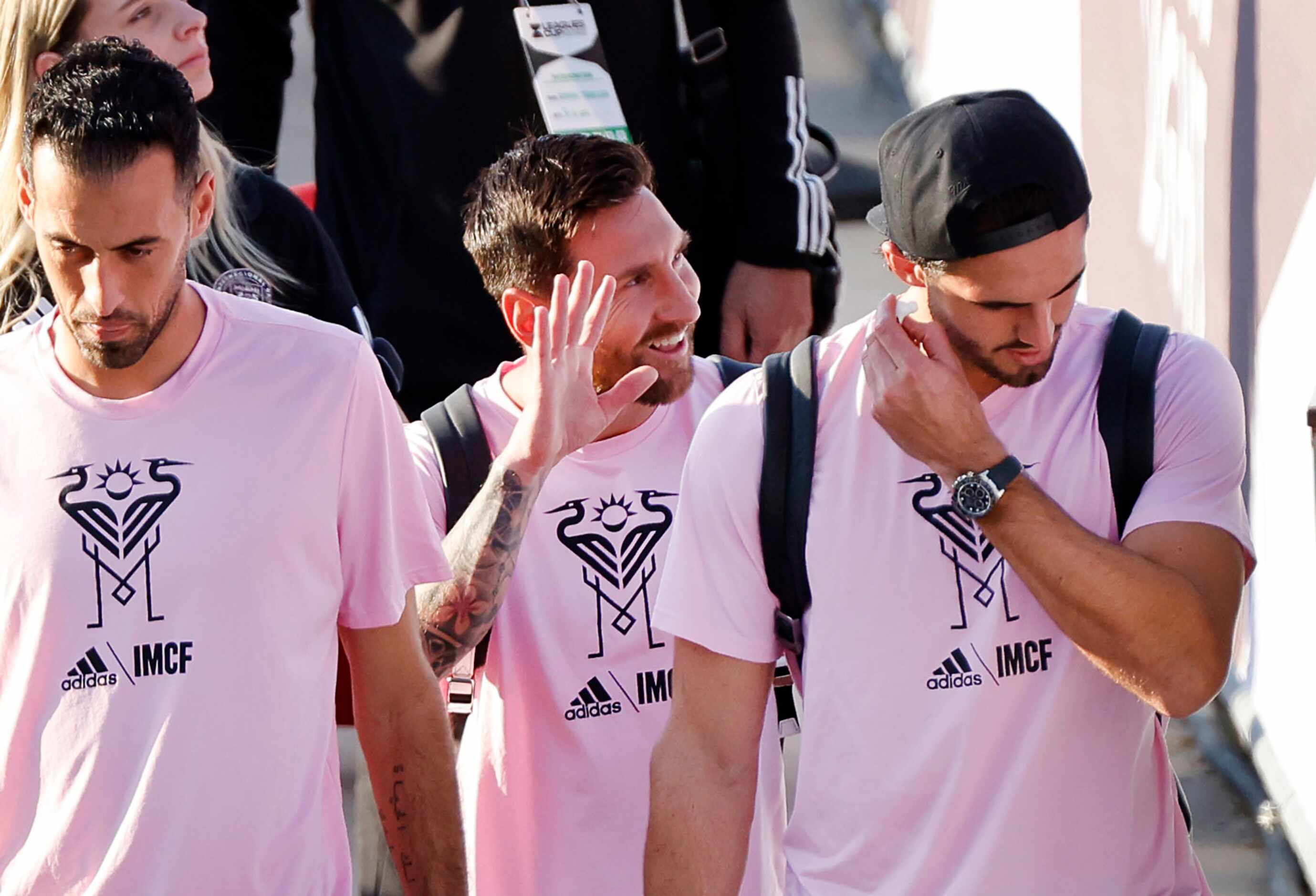 Inter Miami forward Lionel Messi (center) waves to a fan as he arrives with his teammates...