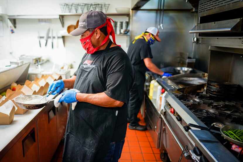 Cruz Garcia (front) and Eduardo Garcia wear face masks as they work in the kitchen at TJ's...