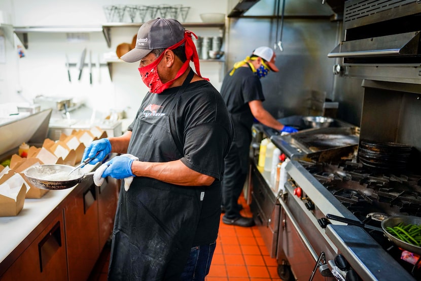 Cruz Garcia (front) and Eduardo Garcia wear face masks as they work in the kitchen at TJ's...