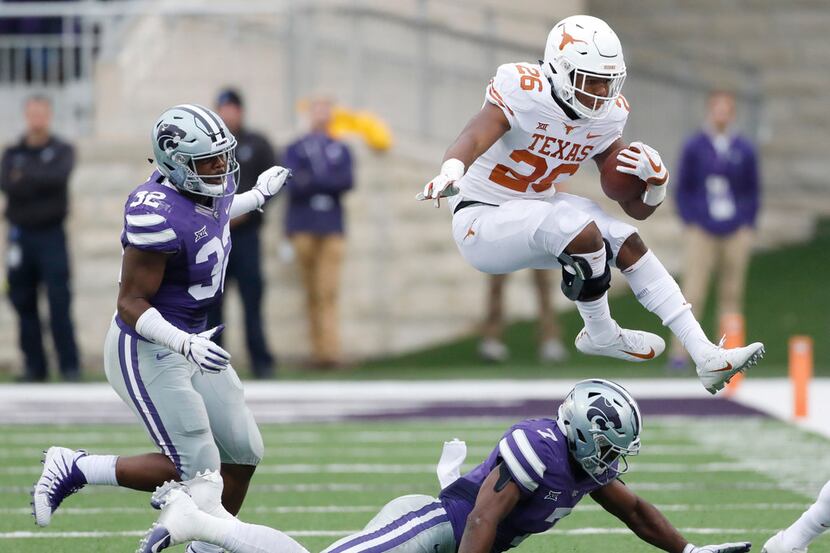 Texas running back Keaontay Ingram (26) jumps over Kansas State safety Eli Walker (7) as he...