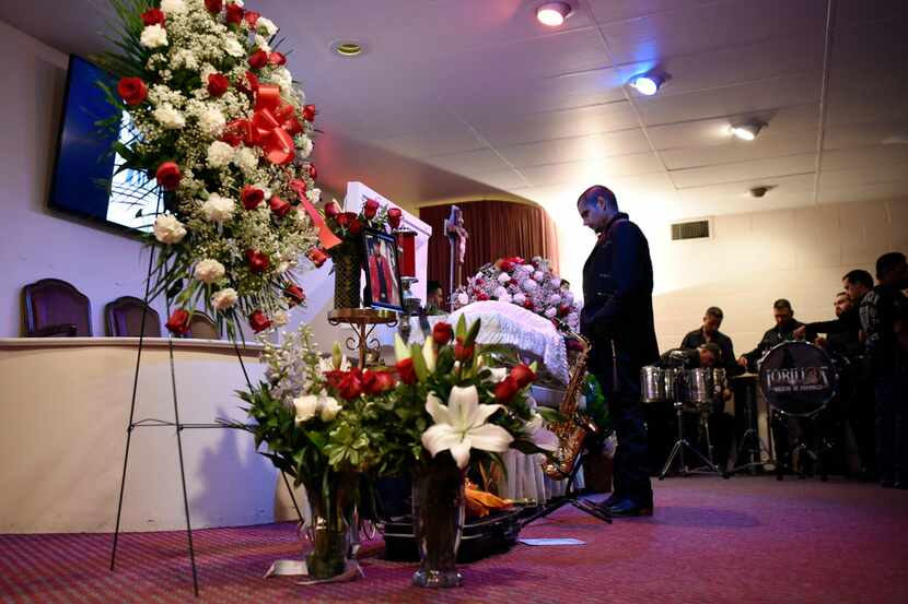 A bandmate from the music group Lobillos Musical de Durango pauses in front of the casket of...