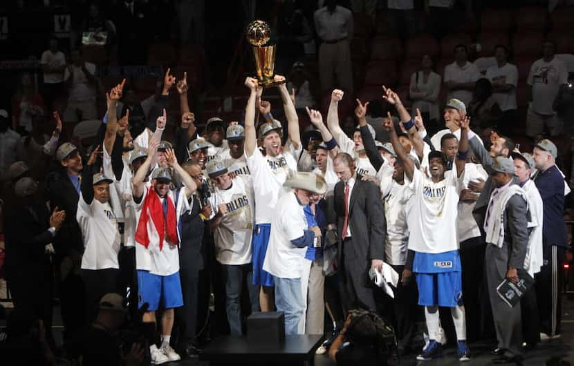 FILE - The Dallas Mavericks celebrate as the team is presented with the Larry O'Brien Trophy...