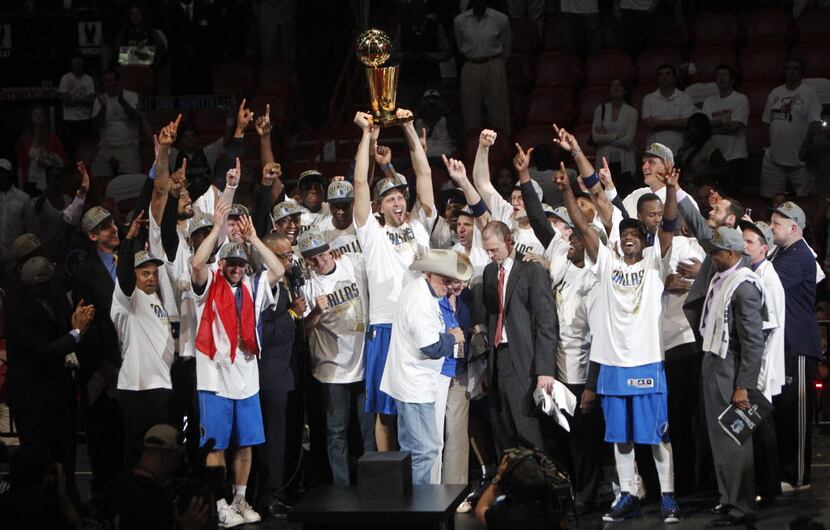 FILE - The Dallas Mavericks celebrate as the team is presented with the Larry O'Brien Trophy...