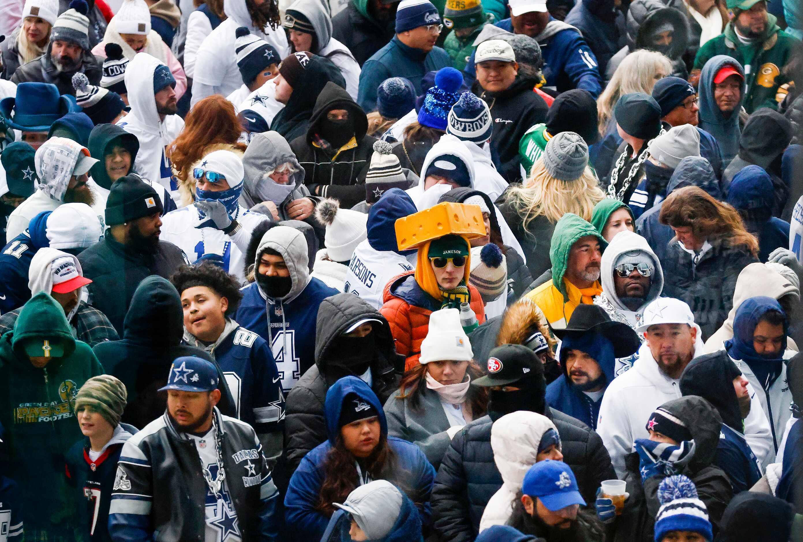 Dallas Cowboys and Green Bay Packers fans keep warm on the west plaza as they wait to get...