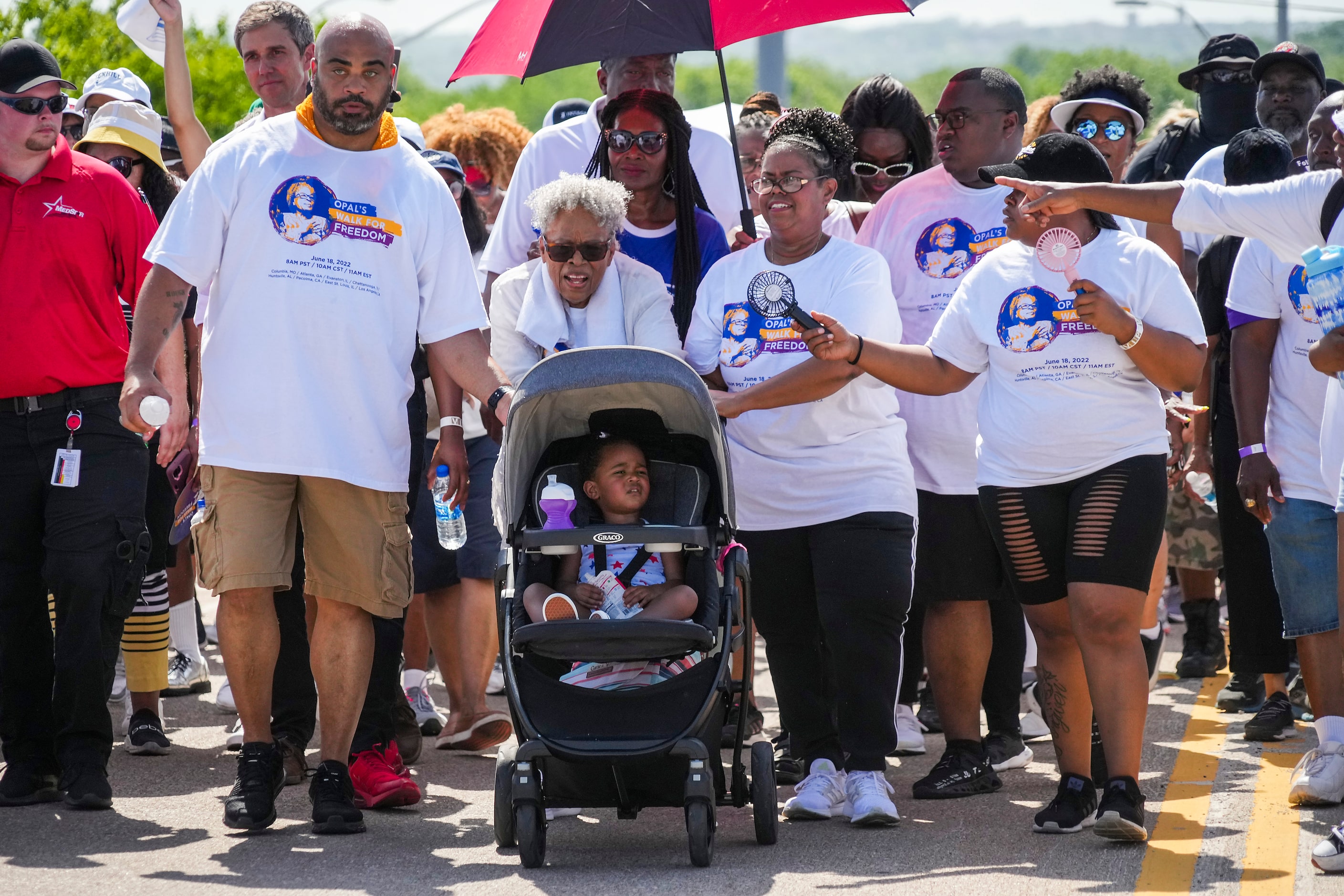 Opal Lee pushes one of her great granddaughters in a stroller as she leads walkers up...