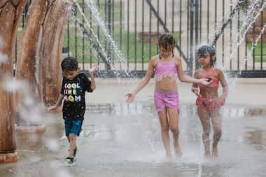 From left, Arturo Coca, 8, Maricla Coca, 7, and Madalyn Lange, 5, walk through a water...