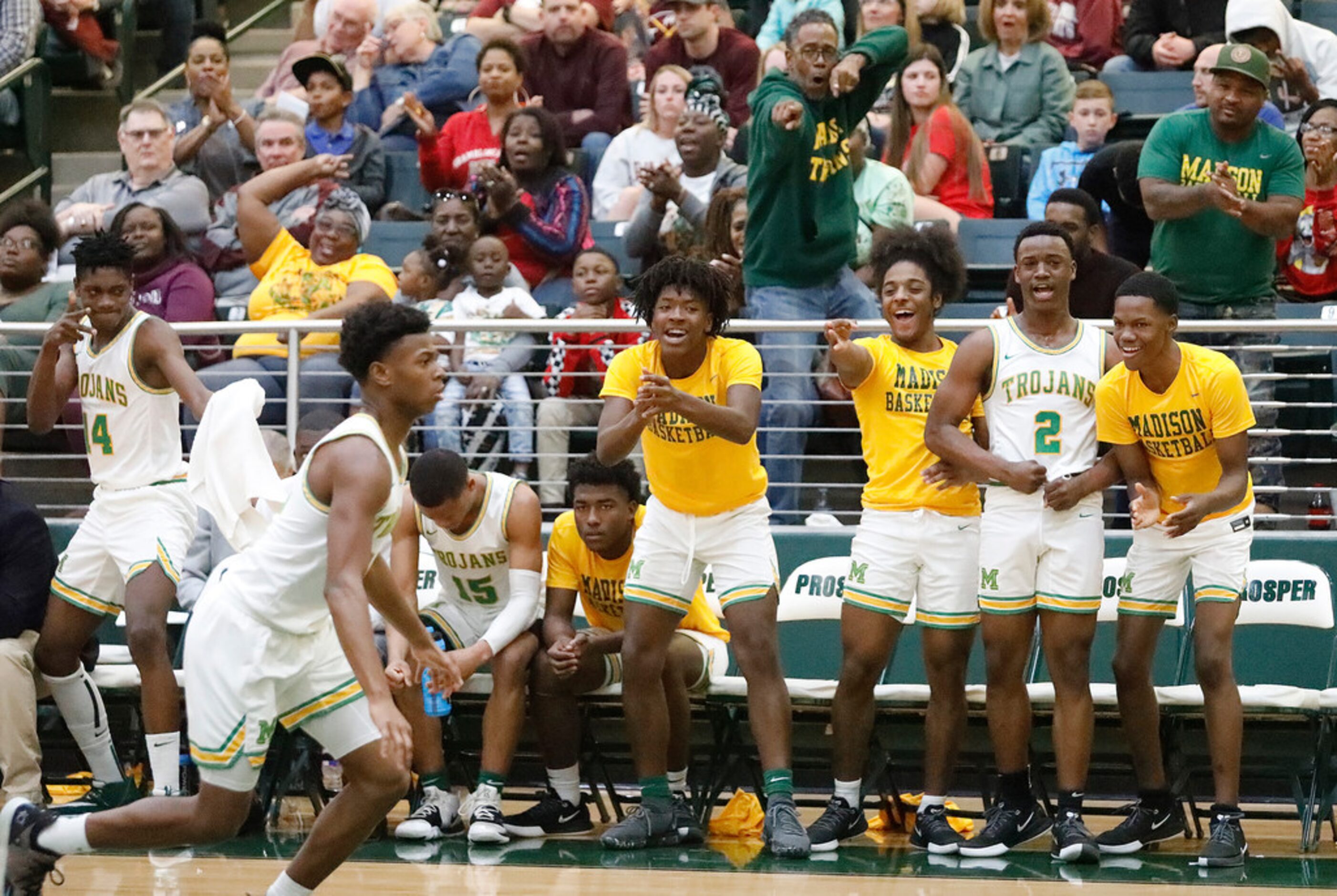 The Madison High School bench cheers as they begin to pull away during the second half as...