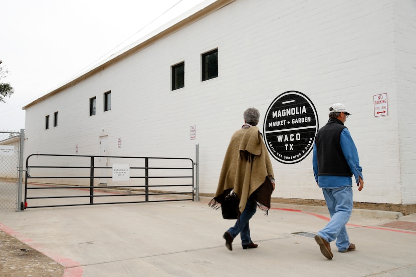 Shoppers pass by the gate crossing a driveway on the south end of Chip and Joanna Gaines'...