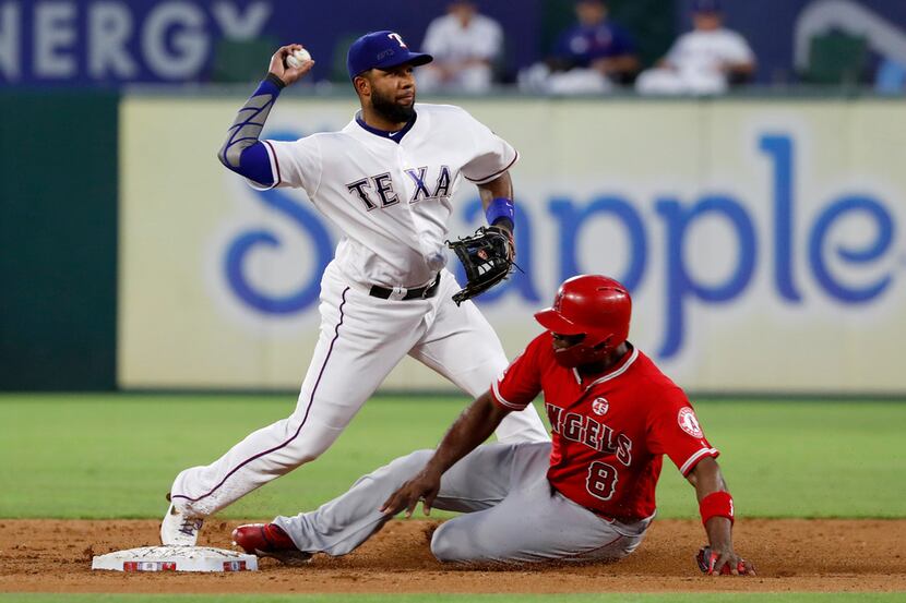 Texas Rangers shortstop Elvis Andrus throws to first for the double play after forcing out...
