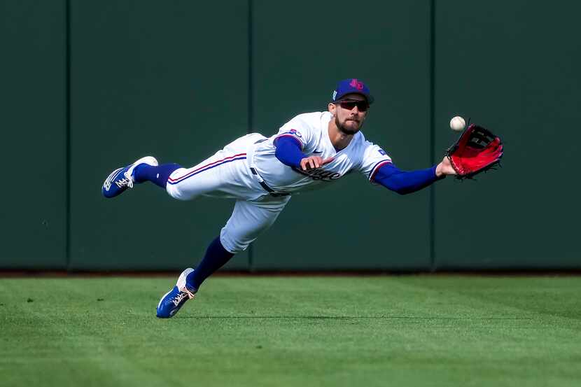 Texas Rangers center fielder Eli White dives for a line drive off the bat of the Cincinnati...