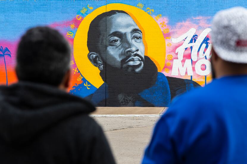 Hatziel Flores (left) and Jeremy Biggers look at their mural dedicated to the late rapper,...