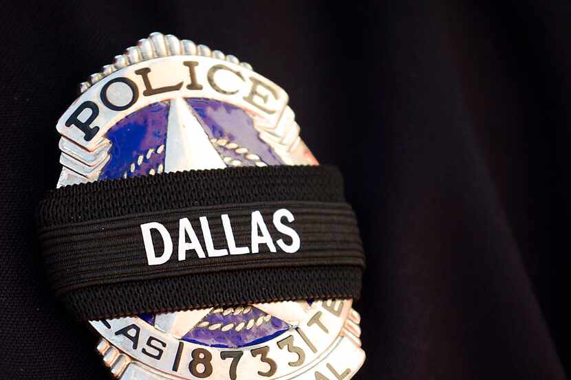 A black band covers a Dallas police corporal's badge after the ambush that killed four...