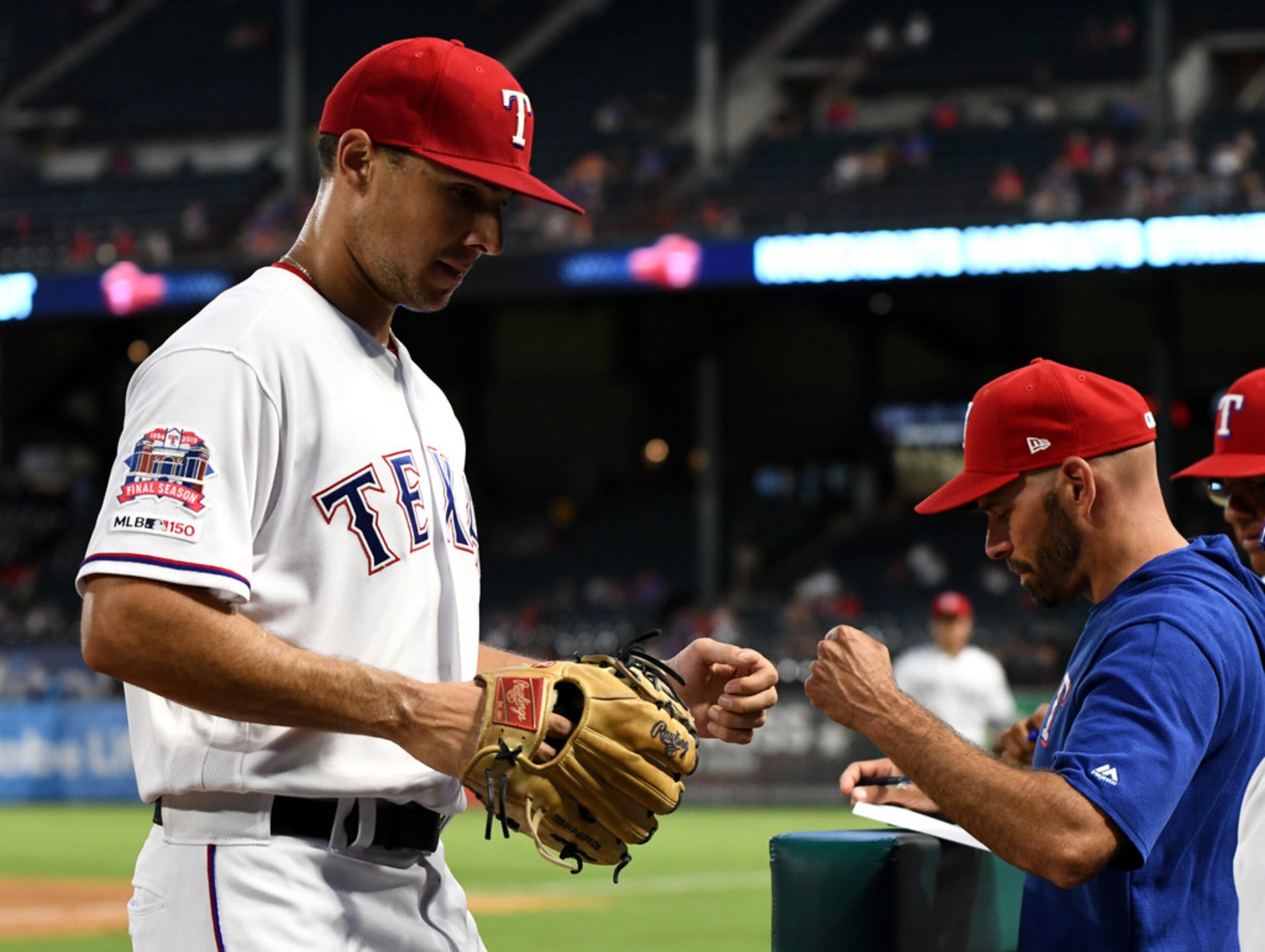 ARLINGTON, TEXAS - AUGUST 20: Brock Burke #70 of the Texas Rangers first bumps Chris...