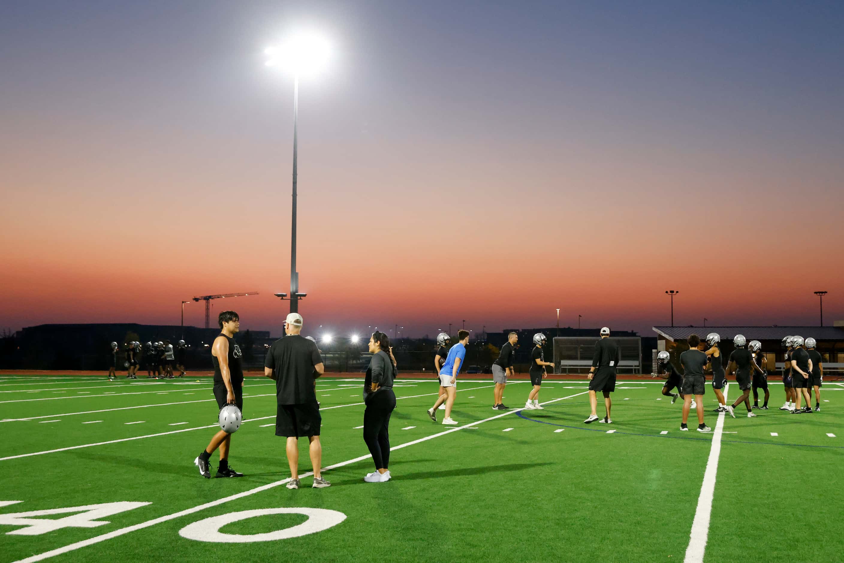 The sun rises during an early morning football practice at Panther Creek High School,...