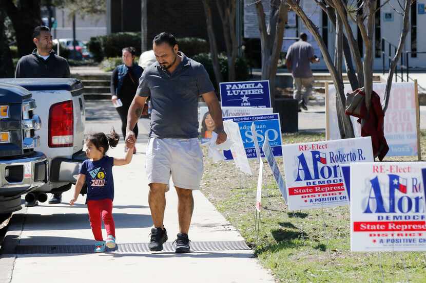 Armando Vergara walks his daughter Evylin, 3, past the Dallas County Government Center,...