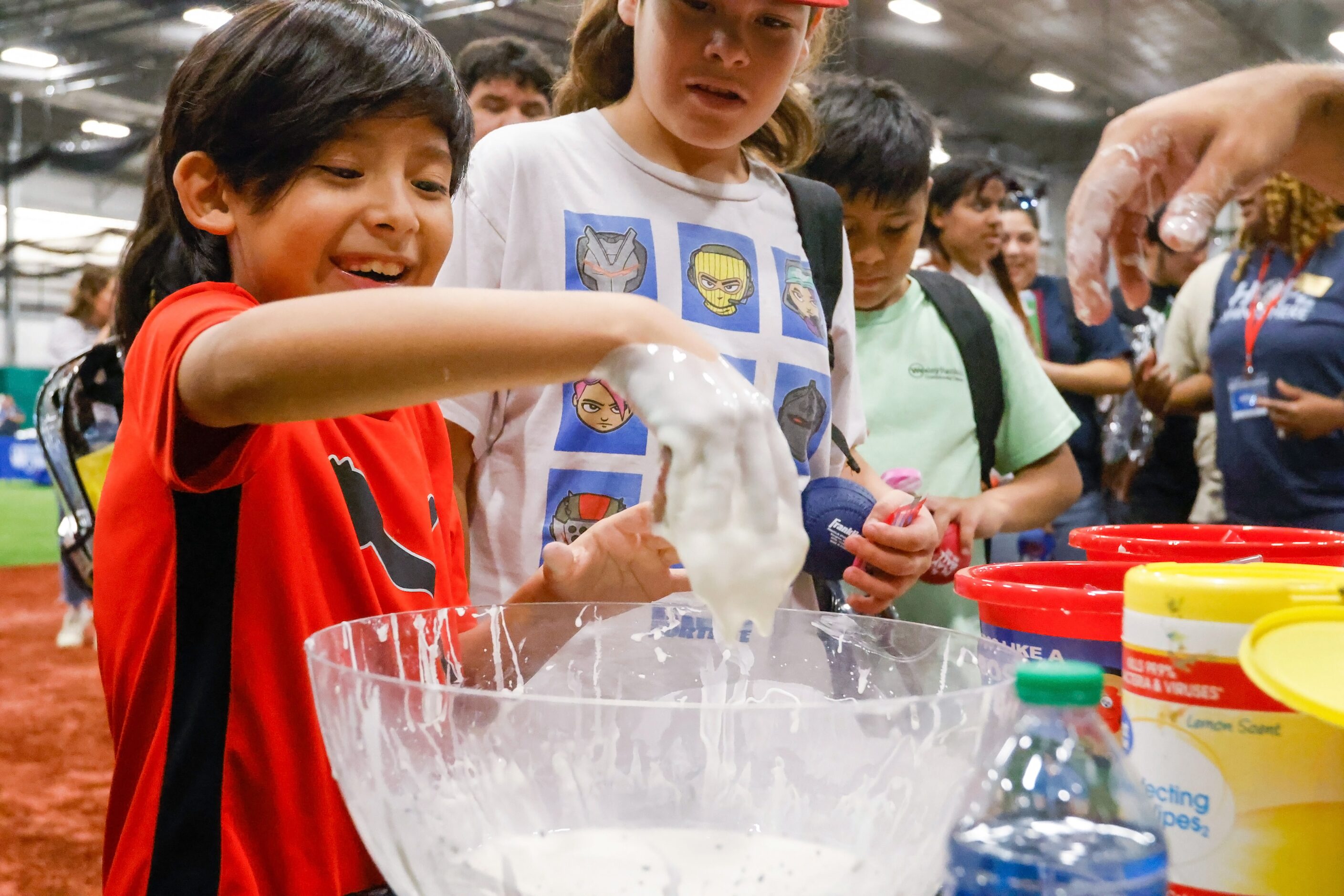 Adam Muniz (front), 9, pulls his hand out of a bowl of slime brought by Buckner to the...