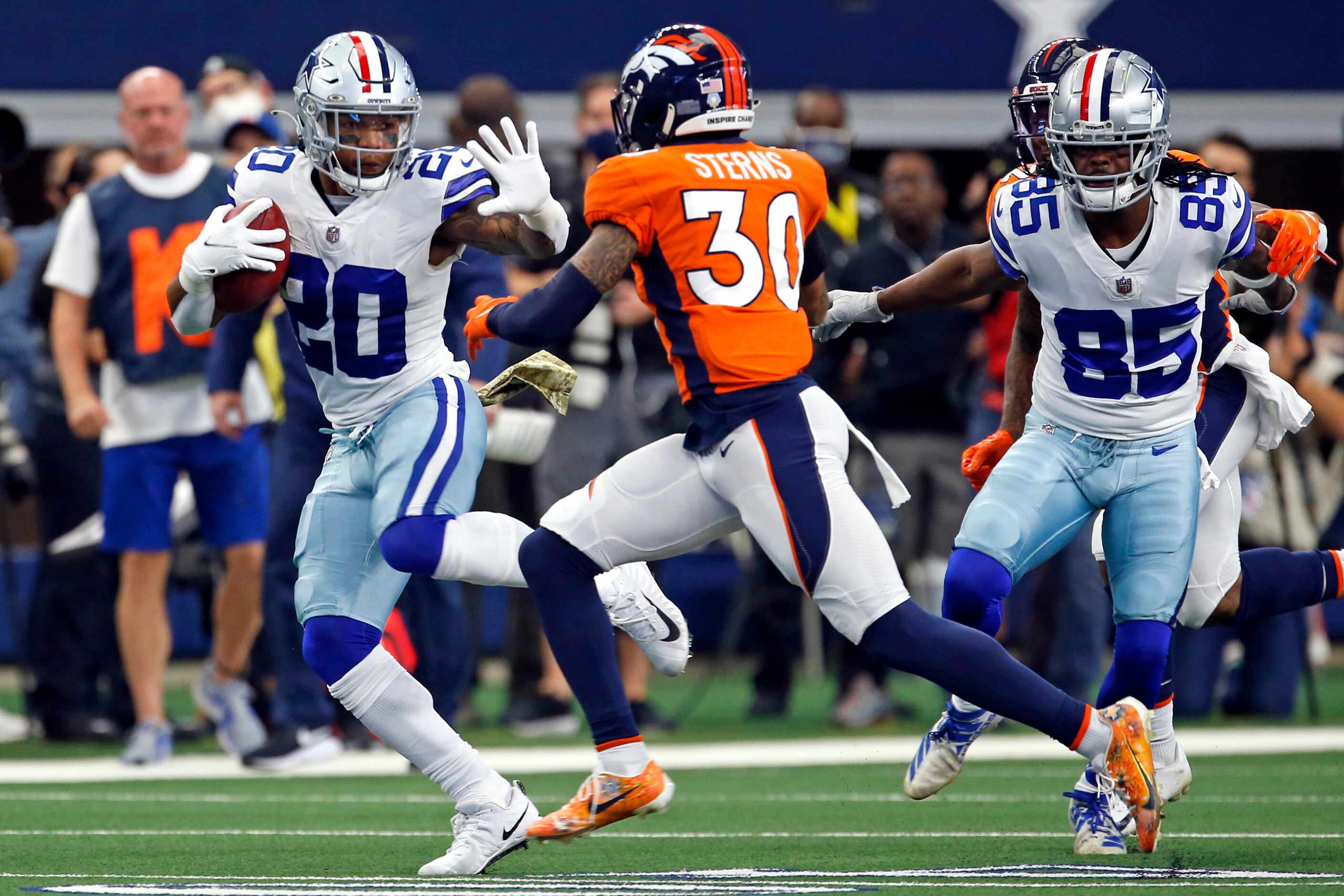 Dallas Cowboys running back Tony Pollard (20) tries to hold off Denver Broncos safety Caden...