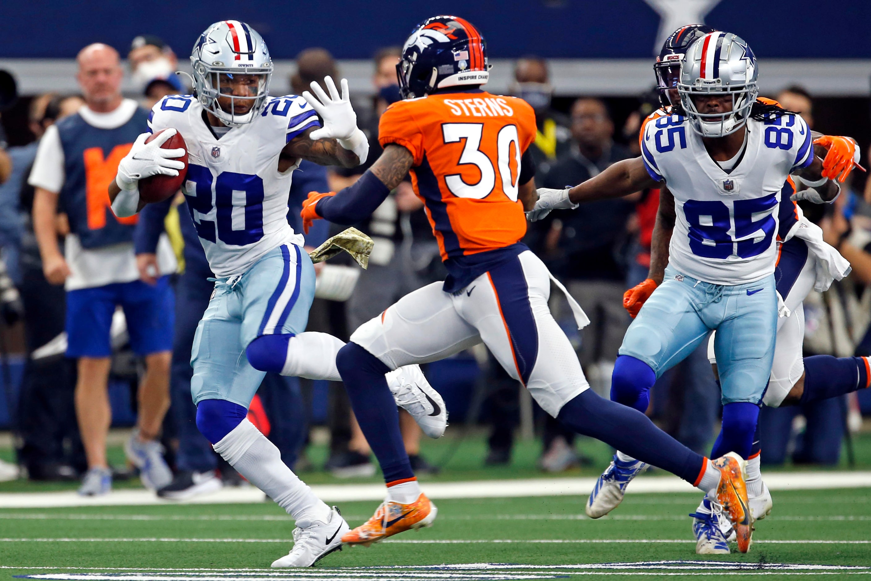 Dallas Cowboys running back Tony Pollard (20) tries to hold off Denver Broncos safety Caden...