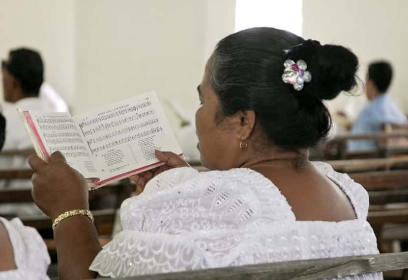 Micronesian women dressed in white lace sing four-part choral harmony during a church...