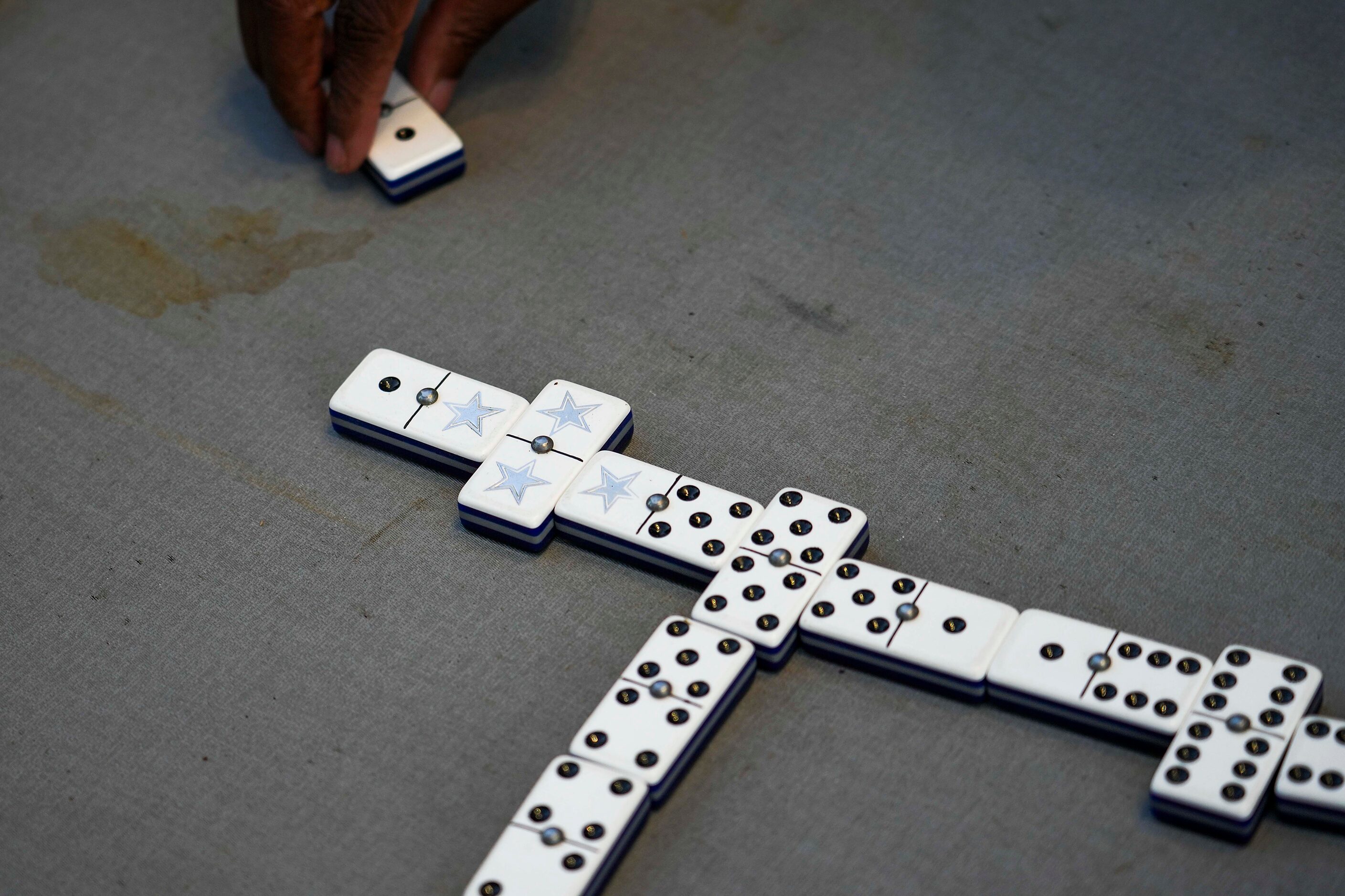 Fans play dominoes outside the stadium while tailgating before an NFL football game between...