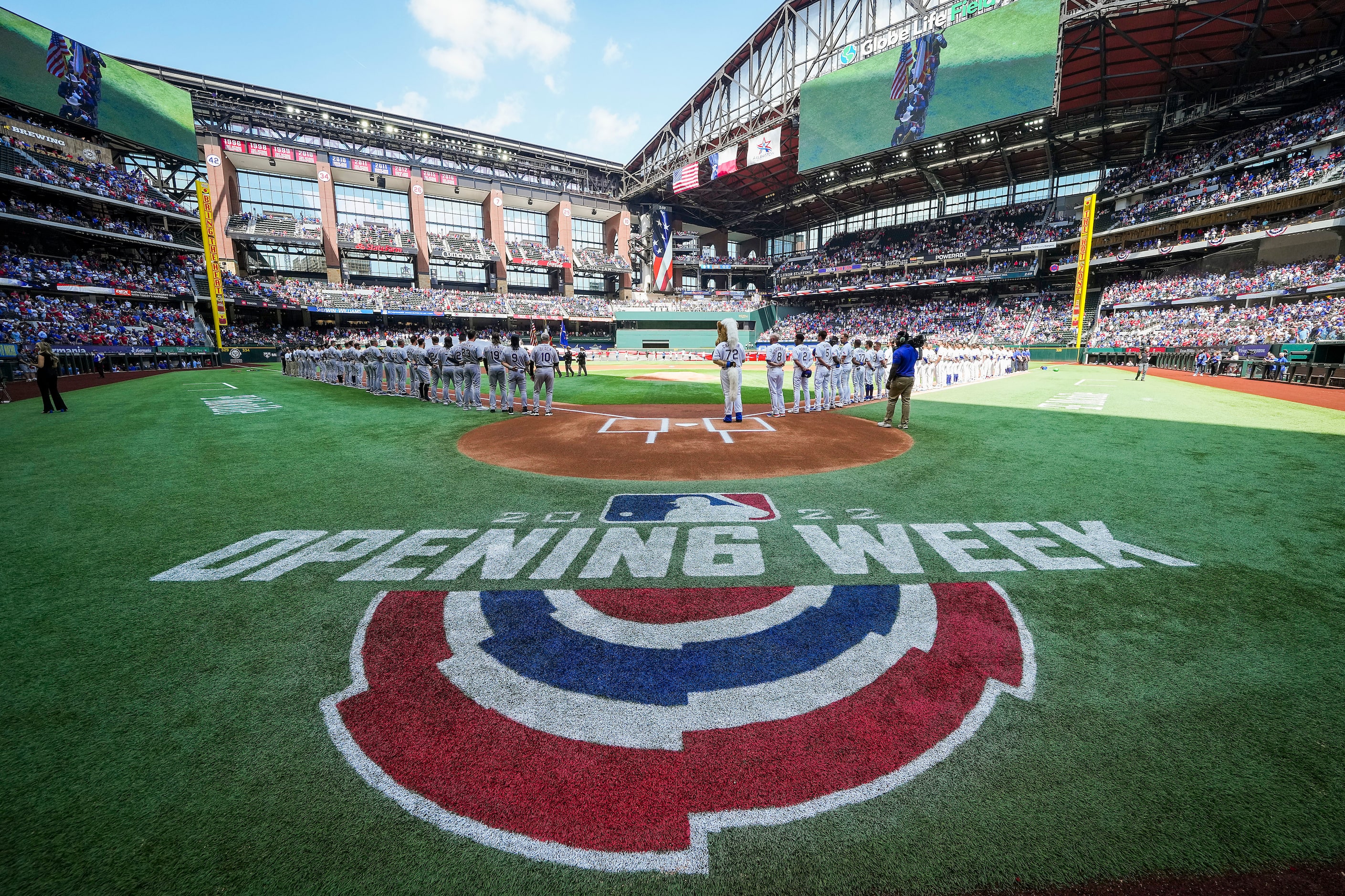 The players stand for the national anthem before the Texas Rangers home opener against the...