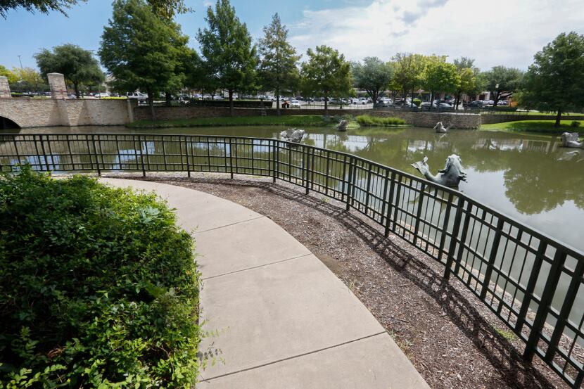 A sidewalk winds around one of the ponds at The Arbors shopping center located at the...