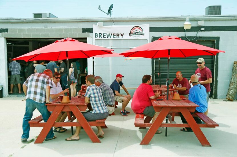 
People smoke cigars on the patio of Four Bullets Brewery.
