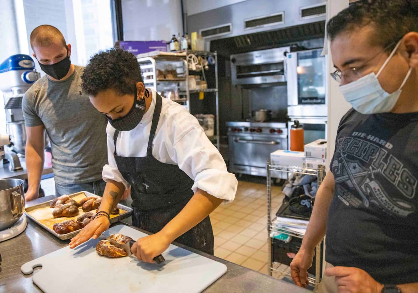 Pastry chef Tristyn Williams, 17, cuts into a pretzel as Police Major Juan Salas (left) and...