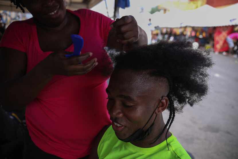 Jean Rodmique, 32, from Haiti, sits on a chair while his wife braids his hair, Wednesday,...