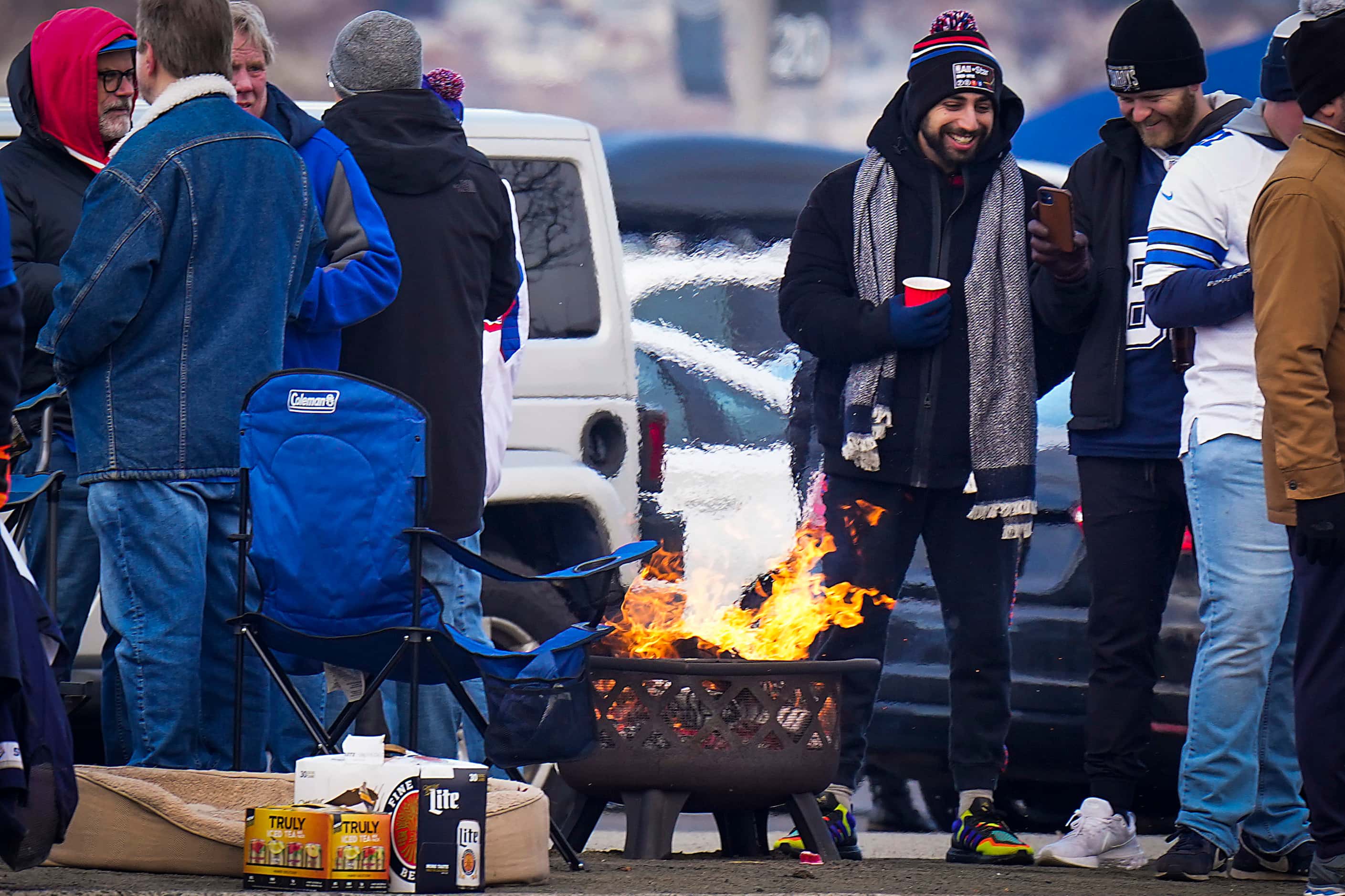 Fans gather around a fire while tailgating before an NFL football game between the New York...