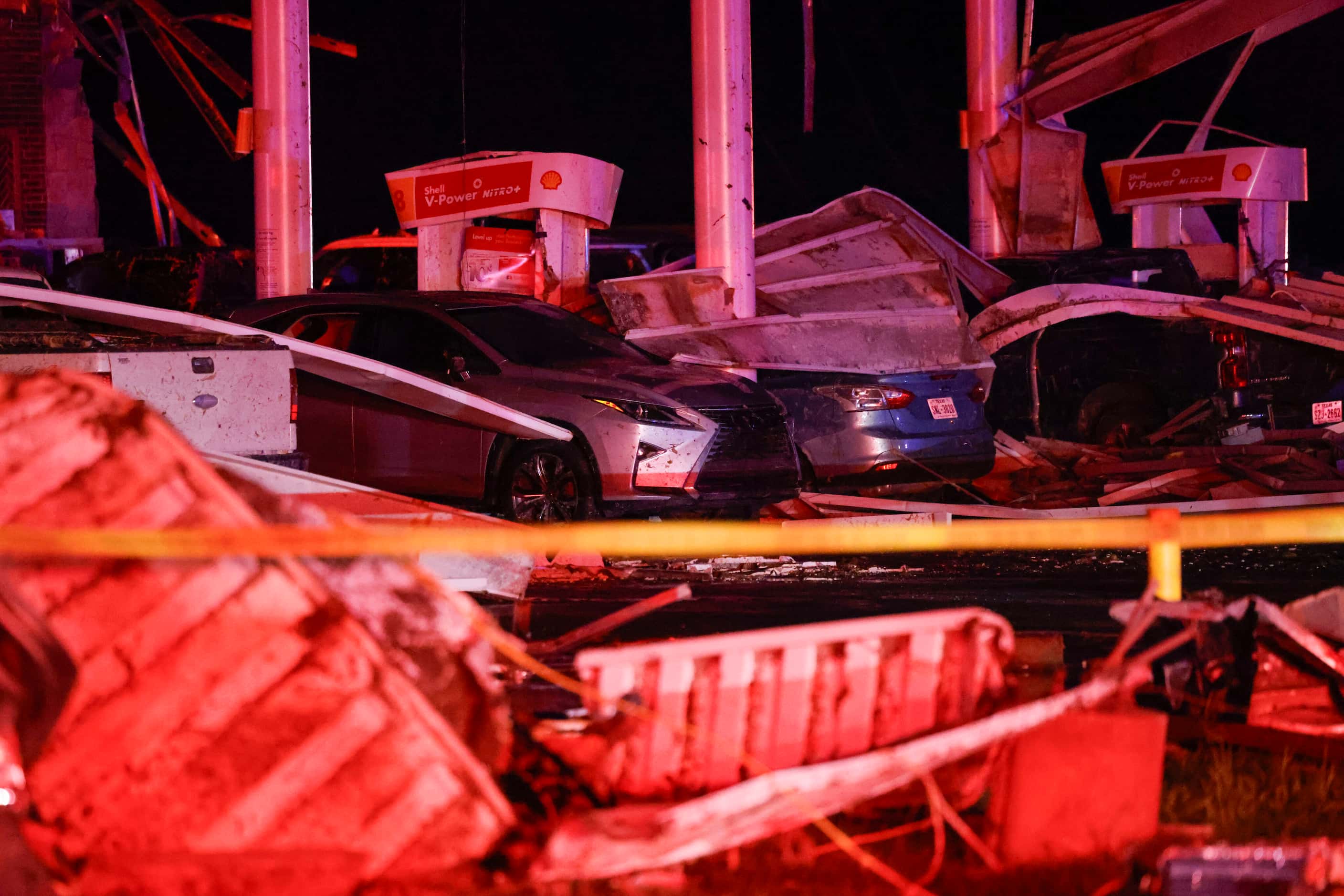 Several vehicles sit underneath the remnants of a Shell gas station after a tornado moved...