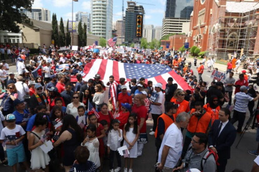 La gente se alista para marchar con una bandera de Estados Unidos en el centro de Dallas....