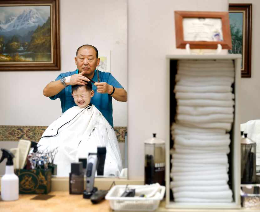 Hairstylist GapJun Lee cuts four-year-old Yoon Koh’s hair at Asian Barber Shop in a...