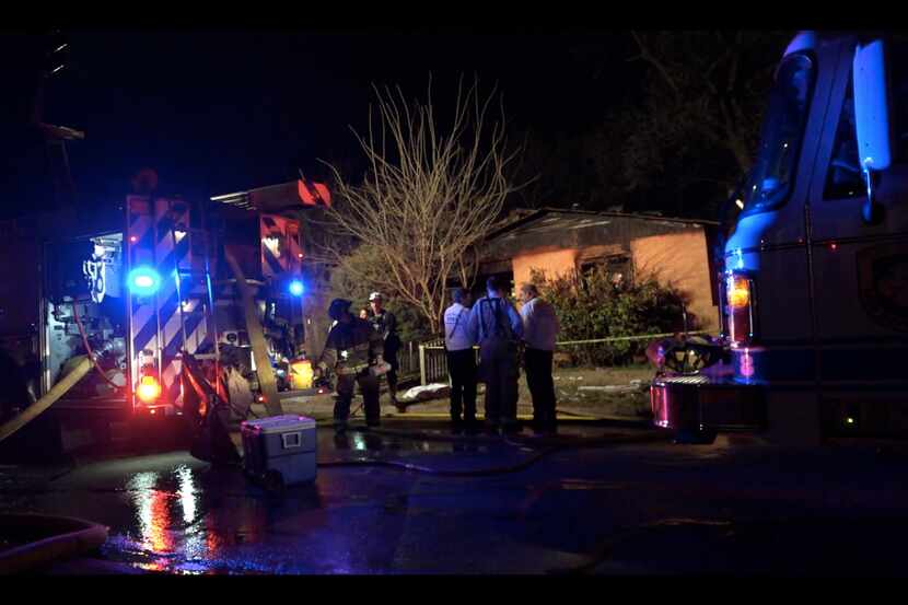 Fire officials survey the scene outside a home that burned Wednesday morning in Fort Worth....