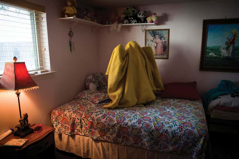Kara Zartler, 17, who has cerebral palsy and severe autism, wraps herself in her blanket,...