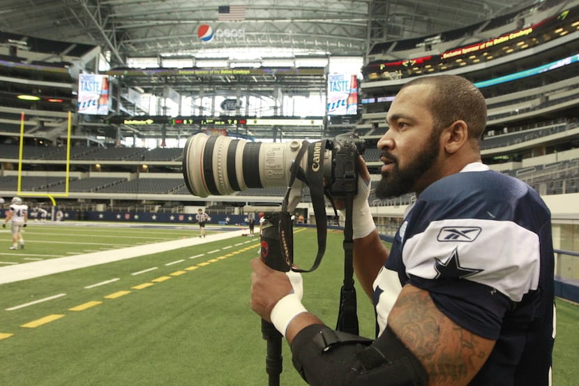 Dallas Cowboys defensive end Jason Hatcher (97) tries out a professional camera and lens...