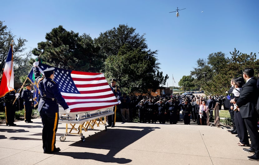 The Dallas Police helicopter performs a flyover as the U.s. flag is presented above the...