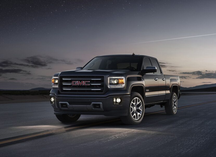 The 2014 GMC Sierra All Terrain front three quarter view at dusk shows the projector beam...